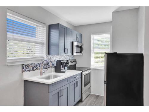a kitchen with a sink and a black refrigerator at Rustic Retreats Beachy 1BR for 4 guests in the heart of Fort Lauderdale in Fort Lauderdale
