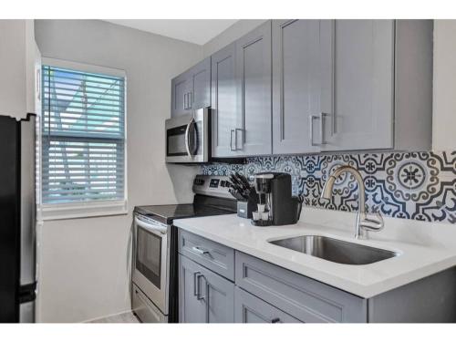 a white kitchen with a sink and a stove at Rustic Retreats Cozy 1BR For 4 Guests In The Heart Of Fort Lauderdale in Fort Lauderdale