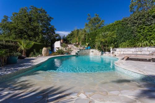 a swimming pool in a backyard with a stone wall at La Bergerie in Saint-Jeannet