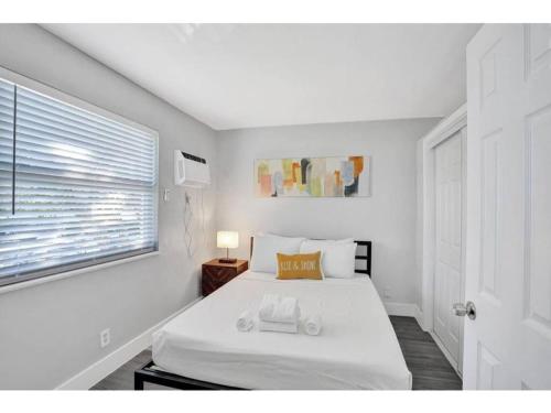 a bedroom with a white bed and a window at Rustic Retreats Cozy 1BR For 4 Guests Minutes From Las Olas in Fort Lauderdale