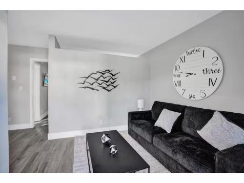 a living room with a couch and a clock on the wall at Rustic Retreats Cozy 1BR For 4 Guests Minutes From Las Olas in Fort Lauderdale