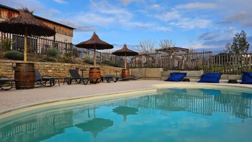une piscine avec chaises et parasols dans une cour dans l'établissement L'Escale Occitane, à Alzonne