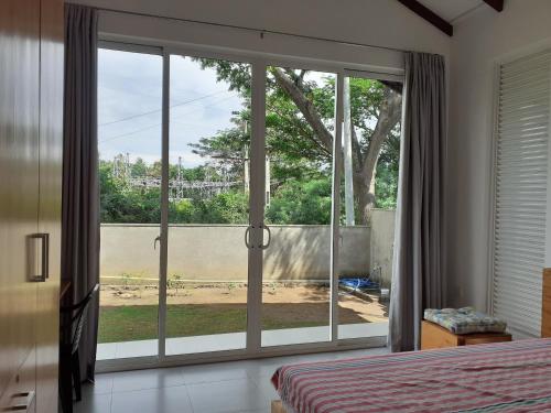 a bedroom with a large sliding glass door with a view at Sathmani in Pallekele Kadawidiya