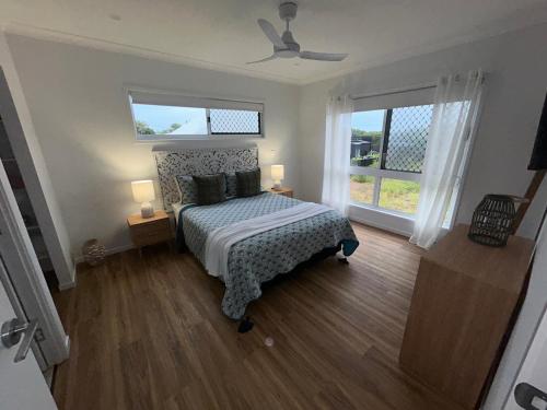 a bedroom with a bed and two windows at Coastal Escape in North Coast