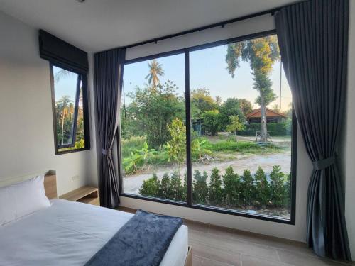 ein Schlafzimmer mit einem großen Fenster mit Blick auf einen Hof in der Unterkunft Na-Tub House in Ban Nua
