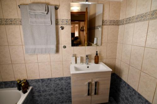 ein Badezimmer mit Waschbecken, Spiegel und Badewanne in der Unterkunft Kostaras Comfort Stay in Dispilio