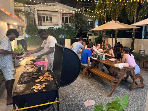 een groep mensen die rond een grill zitten met eten bij Colombo Mount Hostel in Mount Lavinia