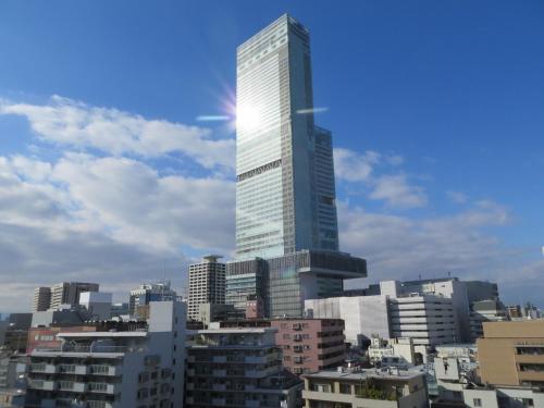 a tall skyscraper in a city with buildings at Hotel Raizan South in Osaka