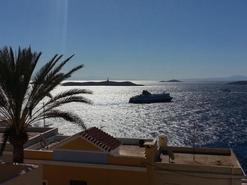 a boat in a large body of water with a palm tree at Veranda Syros House in Ermoupoli