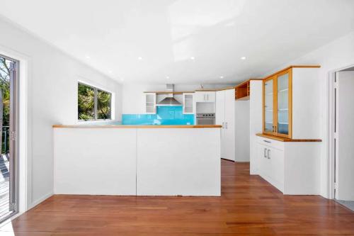 an open kitchen with white walls and wood floors at Sweet North Cote Stay in Auckland
