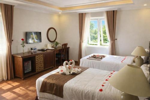 een hotelkamer met twee bedden en een tafel met een spiegel bij Adam Hotel Sa Pa in Sa Pa