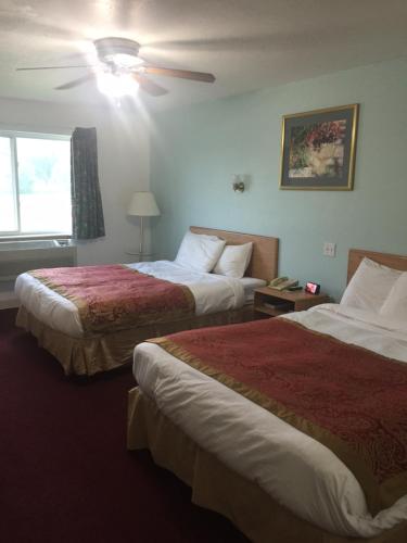 Habitación de hotel con 2 camas y ventilador de techo. en Villa Inn Motel, en Fort Atkinson
