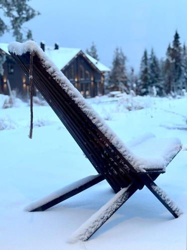 a bench covered in snow in front of a cabin at Lindvallen - Modern Mountain House in Sälen