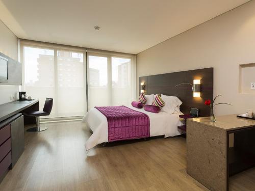 a bedroom with a large bed with a purple blanket at Mercure Bogota BH Zona Financiera in Bogotá