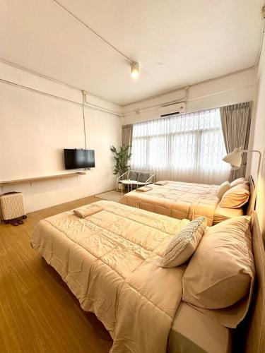 a bedroom with two beds and a flat screen tv at Chatuchak Haus in Bangkok
