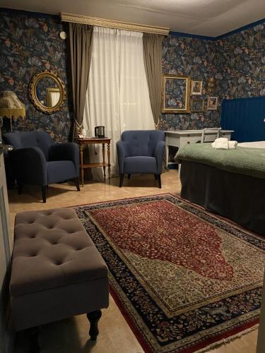 a bedroom with a bed and chairs and a rug at Hotell Tussilago i Essunga in Nossebro