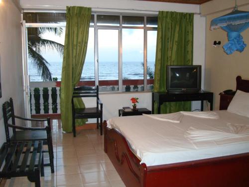 a bedroom with a bed and a tv and a window at Topaz Beach Hotel in Negombo