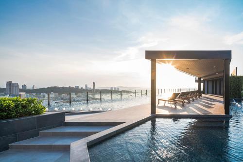 a building with a pool and stairs next to the water at Many Holiday The Base Condo in Pattaya Central