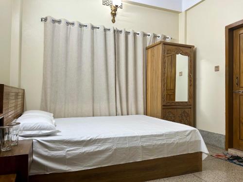 斯里曼加尔乌帕齐拉Sribhumi Homestay的卧室配有白色的床和窗帘