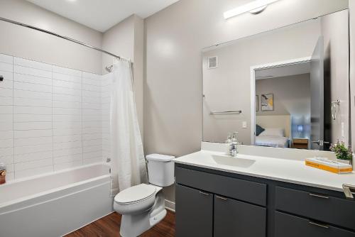 een badkamer met een wastafel, een toilet en een ligbad bij CozySuites Marquee in Minneapolis