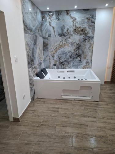a bath tub in a room with a marble wall at Vidik jacuzzi apartment Divcibare in Divčibare
