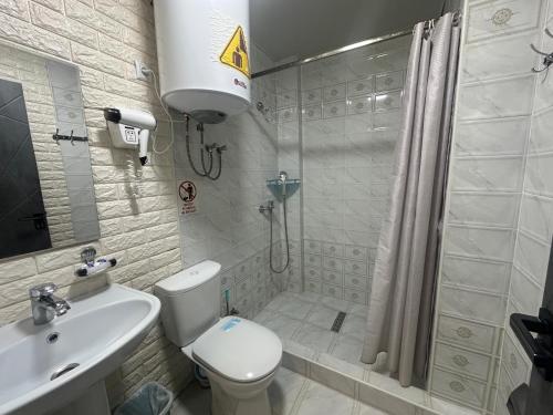 een badkamer met een douche, een toilet en een wastafel bij Boston Hotel in Yakkasaray
