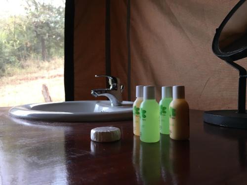 a bathroom counter with three bottles of soap and a sink at Pembeni Rhotia in Karatu