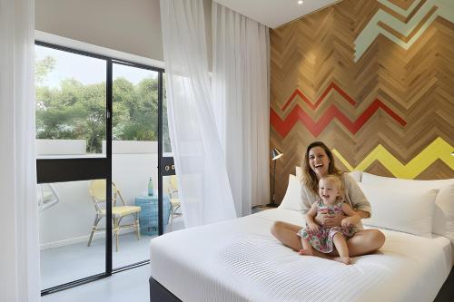 a woman sitting on a bed holding a baby at Cucu Hotel in Tel Aviv