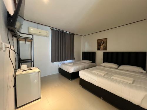 een hotelkamer met twee bedden en een televisie bij Pattaya inn hotel in Pattaya South