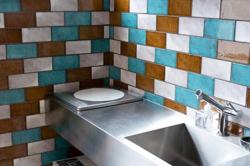 ein Bad mit einem WC in einer gefliesten Wand in der Unterkunft ROTAN東本町 Omura in Matsue