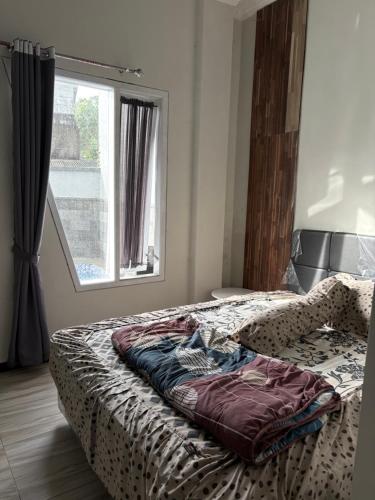 ein Bett in einem Schlafzimmer mit Fenster in der Unterkunft Prabu Villa in Batu