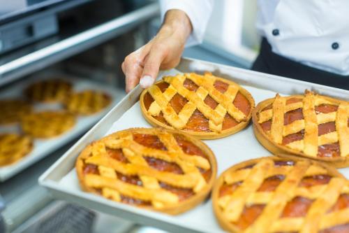 a chef holding a tray with four waffle pies at Hotel Villa Fanny in Cagliari