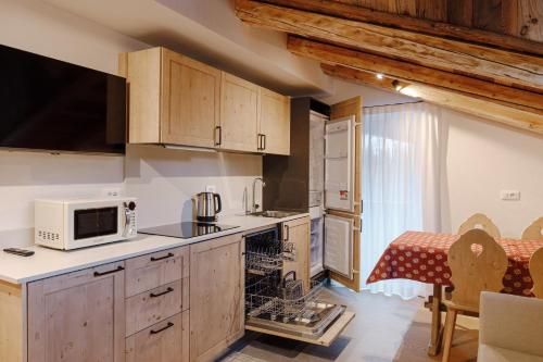 une cuisine avec des armoires en bois et un micro-ondes dans l'établissement Appartamento Sas Ciapel, à Arabba