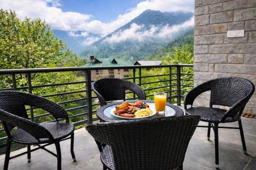un tavolo con un piatto di cibo e bevande su un balcone di Odbostays Manali a Haripūr