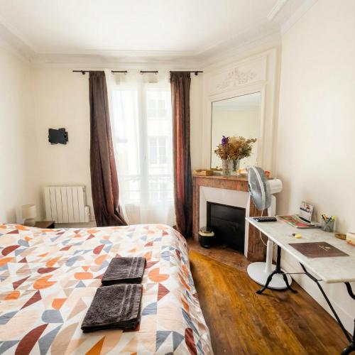 een slaapkamer met een bed, een bureau en een open haard bij A spacious room in a strategic area in Montrouge