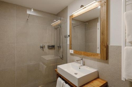 un bagno con lavandino e doccia con specchio di Appartamento Aurone ad Arabba