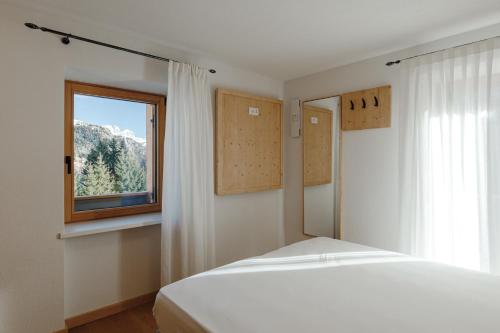una camera da letto con un letto bianco e una finestra di Appartamento Aurone ad Arabba