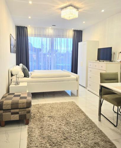 a bedroom with a large white bed and a tv at Schneider Apartments in Neustadt am Rübenberge
