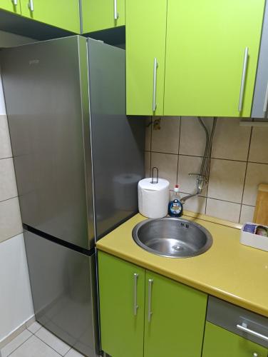 een keuken met een spoelbak en een koelkast bij Apartman 32 in Inđija
