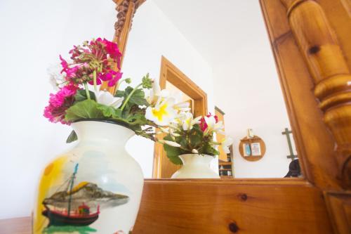 a vase with flowers on a dresser in front of a mirror at Arhontiko Hotel in Foinikion