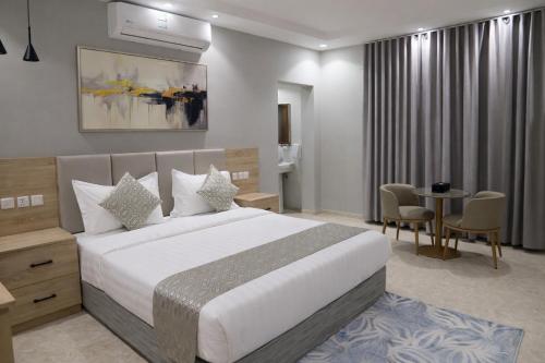 een hotelkamer met een bed en een tafel met stoelen bij اجنحة نزيل & اجنحة الشمال in Tabuk