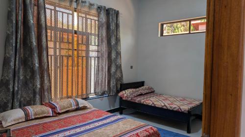 een kamer met 2 bedden en een raam met gordijnen bij Dans place in Moshi