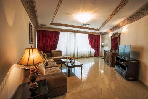 a living room with a couch and a television at Sara Palace Apartments- family only in Kuwait