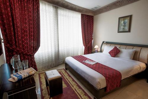 Sara Palace Apartments- family only في الكويت: غرفة فندق بسرير مع ستائر حمراء