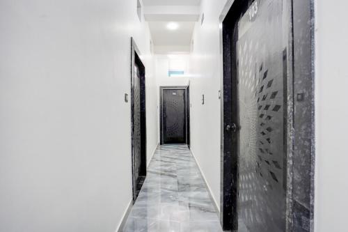 un corridoio con pareti bianche e una porta nera di SPOT ON Hotel Omava Inn a Garhā