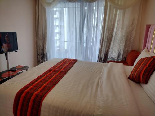 een slaapkamer met een groot wit bed met een raam bij Lenayan at Artesano in Nairobi
