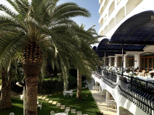 a hotel with palm trees next to a building at Grand Hotel Don Juan in Giulianova