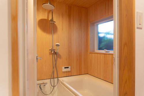 a bathroom with a shower and a tub and a sink at Rotan寺町 in Matsue