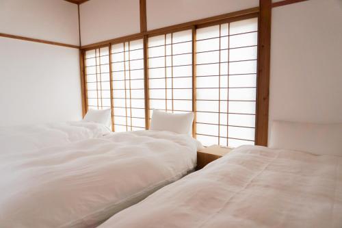 two white beds in a room with a window at Rotan寺町 in Matsue