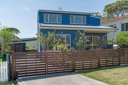 a blue house behind a wooden fence at The Blue Cottage in Ulladulla